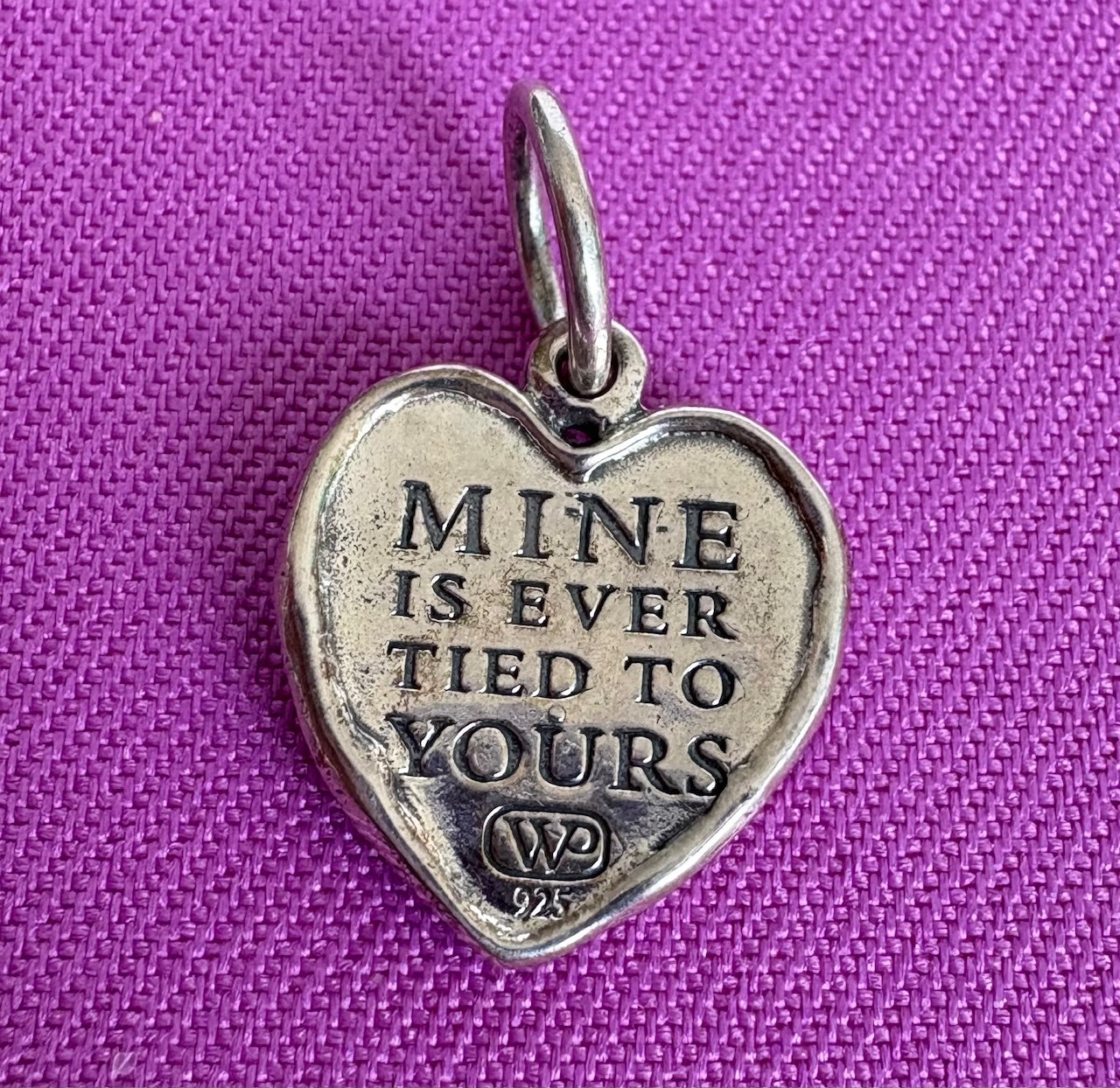 Sterling Silver heart-shaped pendant with engraved text on a purple background
