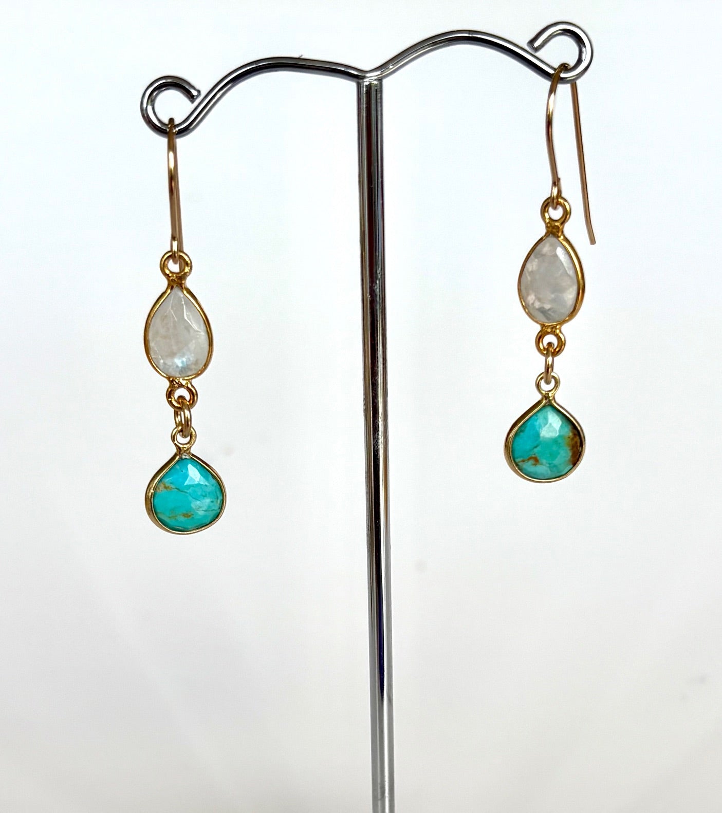 Pair of earrings with teardrop-shaped gemstones on a white background