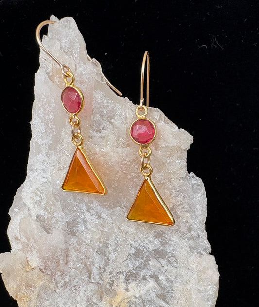 Jolie Esprit gold earrings with pink gemstones and orange triangular stones on a white rock background
