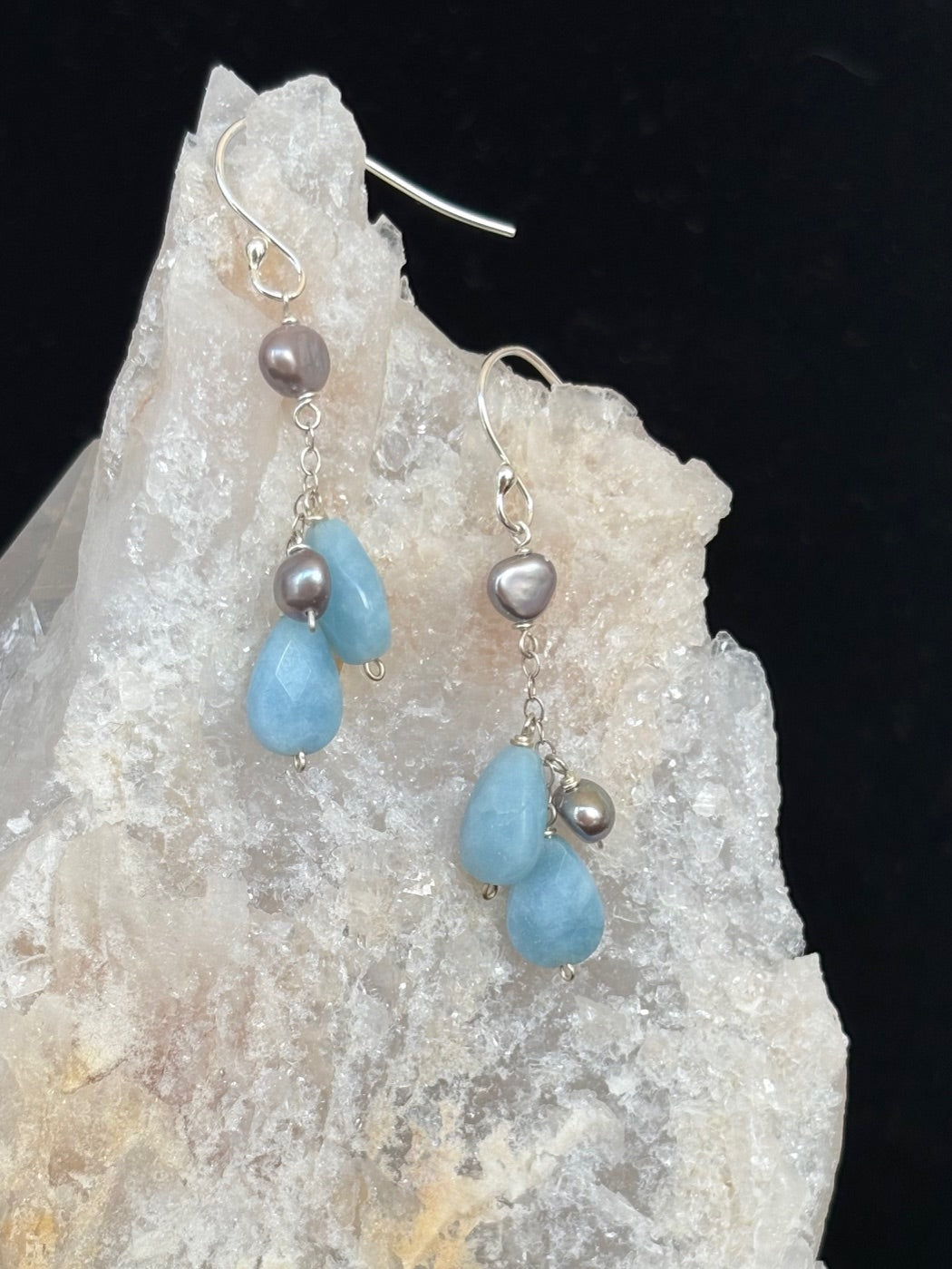 Earrings with blue teardrop-shaped beads and pearls on a crystal background