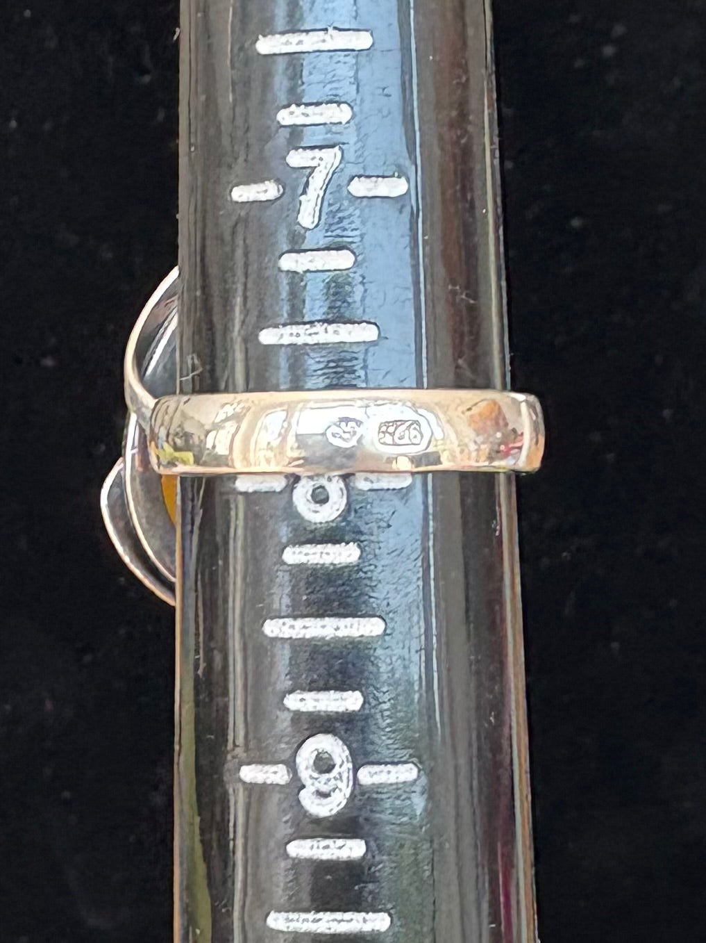 Sterling Silver and amber ring on a black background with measurement scale