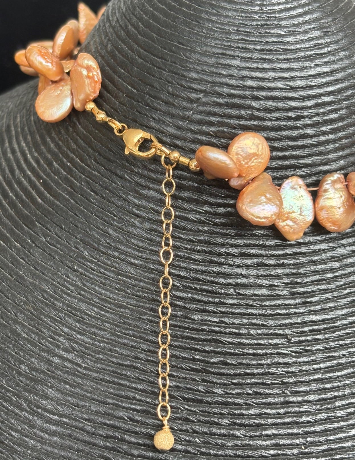 Back of keshi pearl necklace with gold chain on a textured gray background
