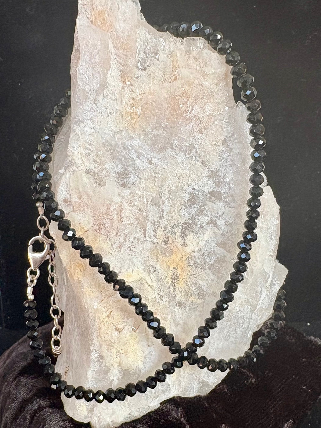 Black gemstone beaded necklace on a stone surface