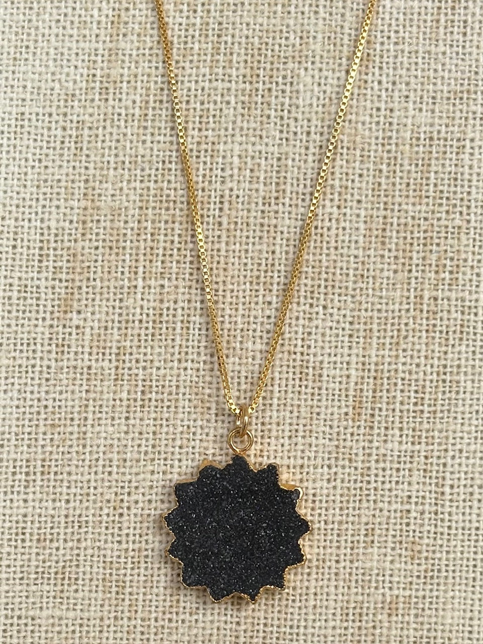 Necklace with a black pendant on a beige fabric background