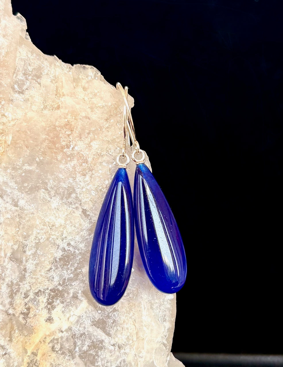 Blue teardrop earrings on a dark background