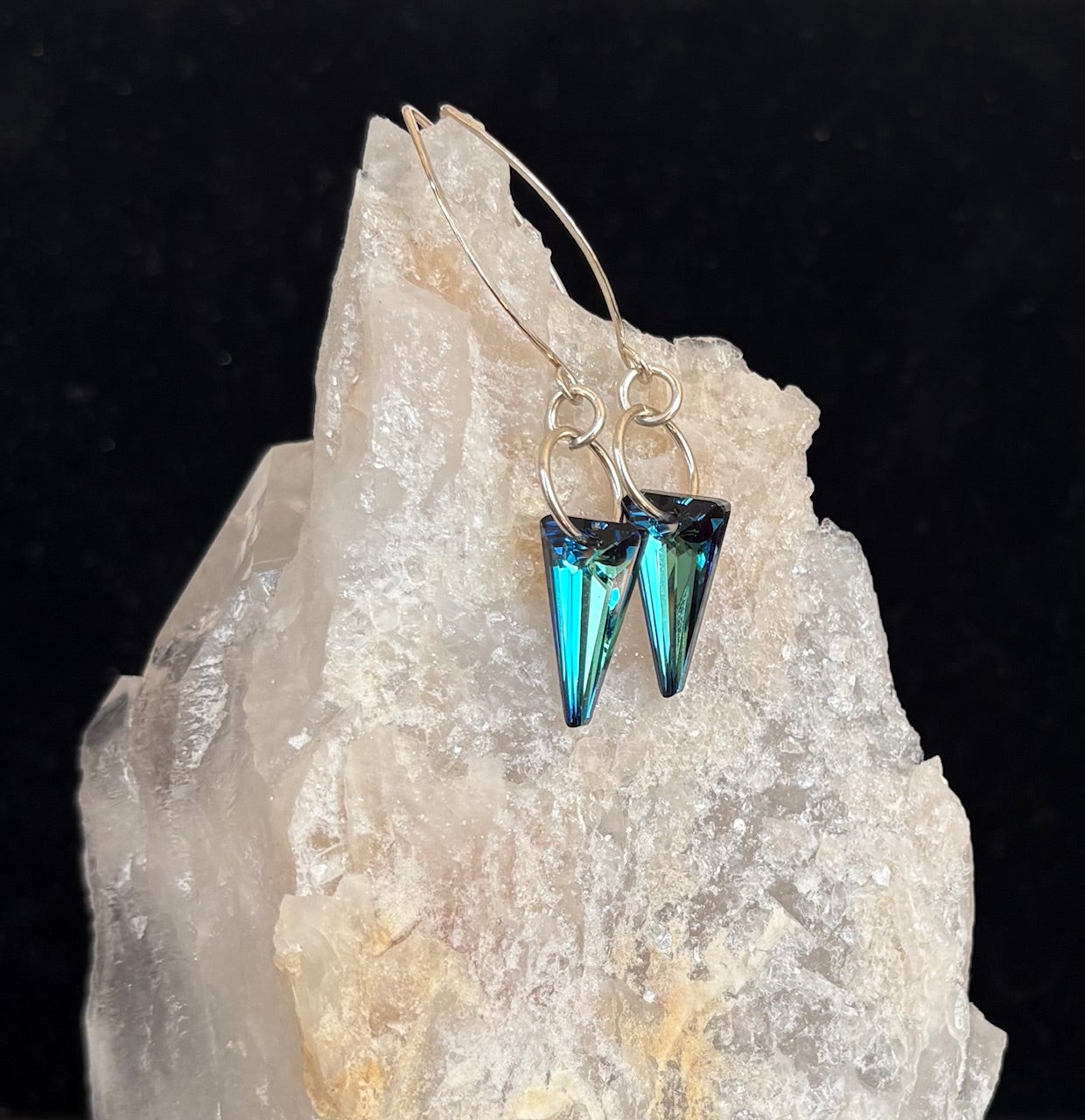Blue crystal earrings on a crystal rock with a black background