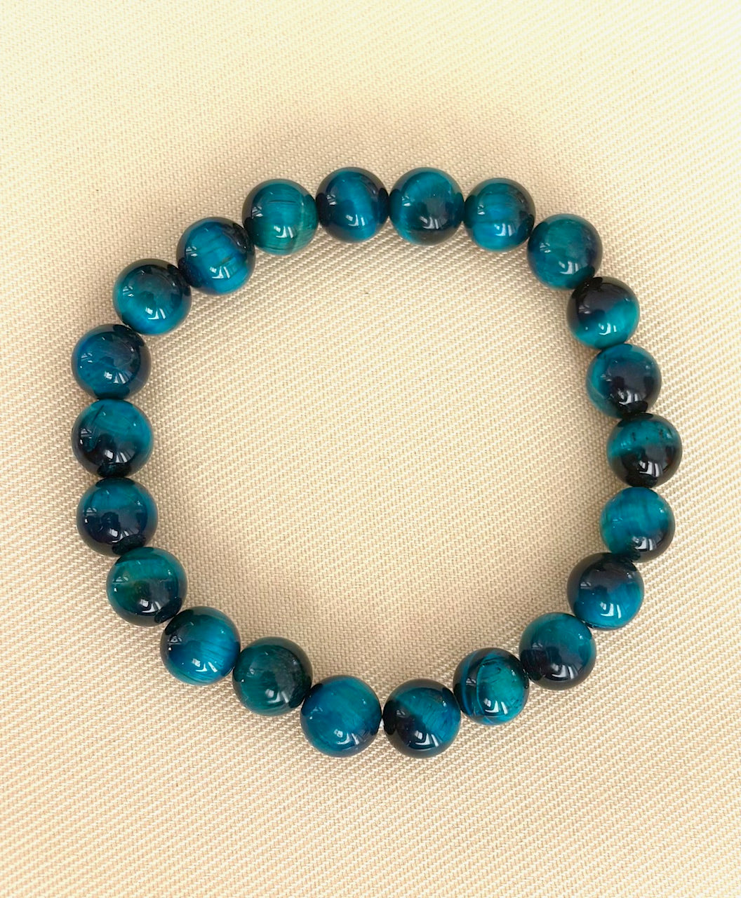 Blue beaded stacking bracelet on a beige fabric background