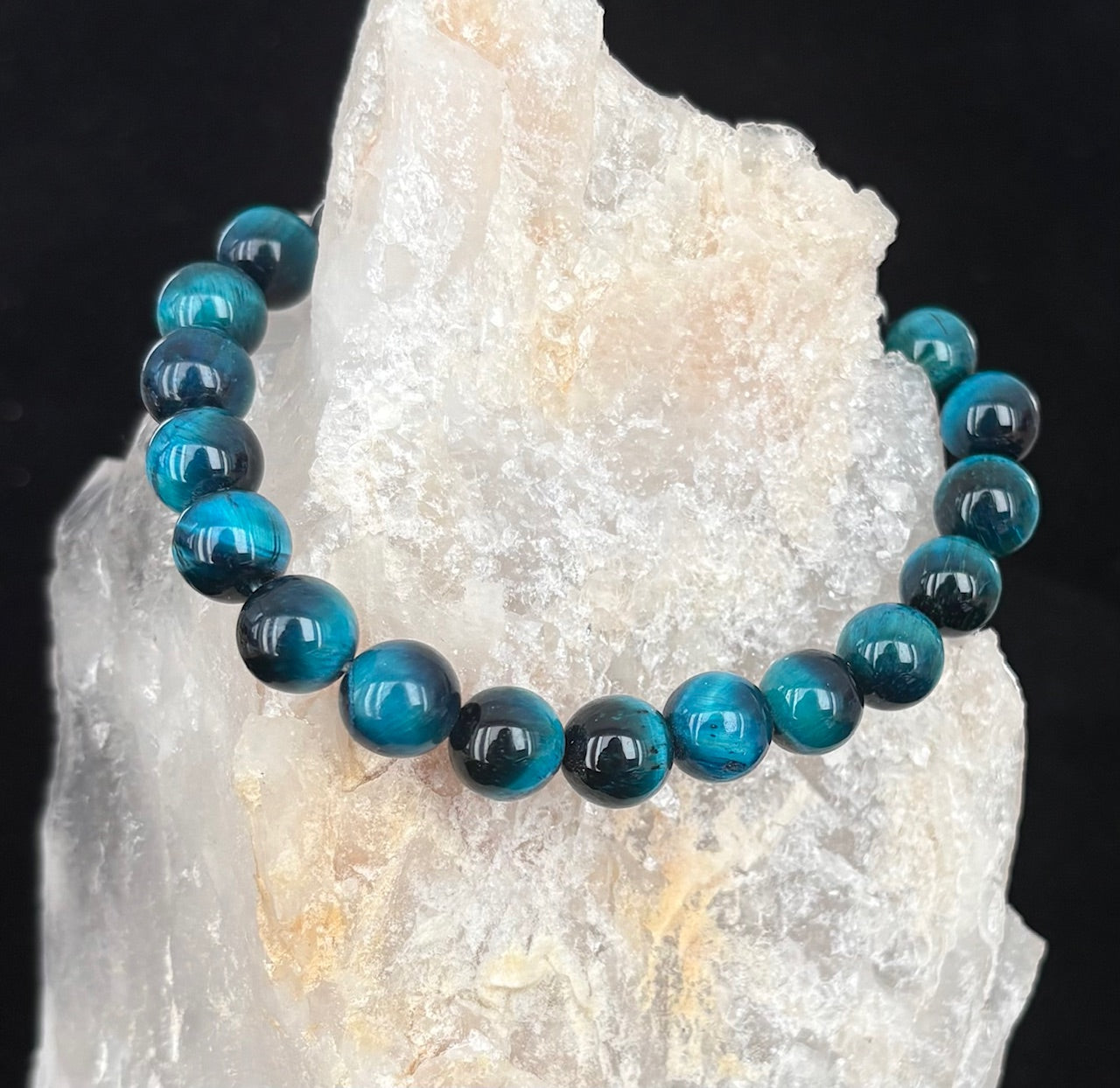 Blue tiger's eye bracelet on a crystal rock with a black background