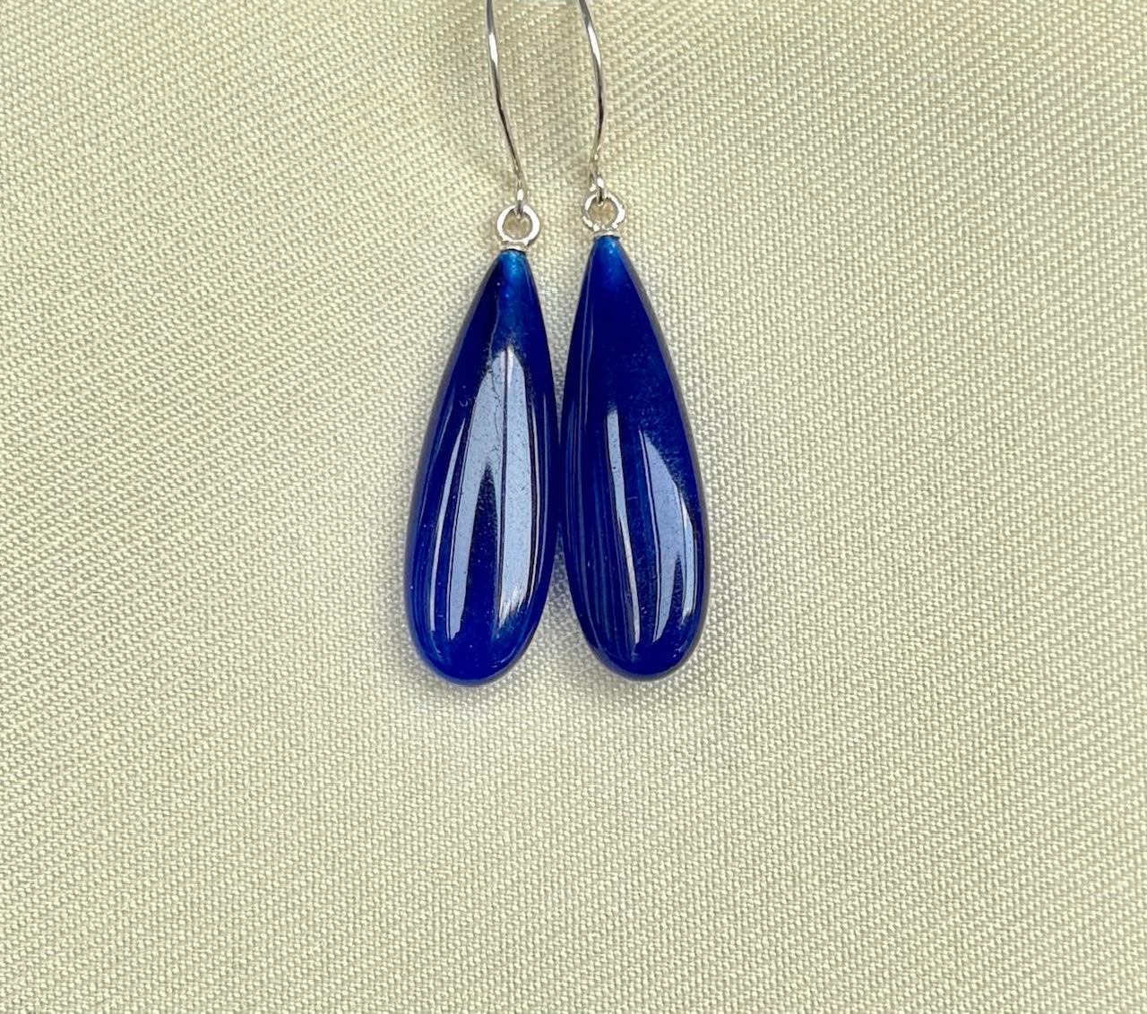 Pair of blue teardrop earrings on a beige background