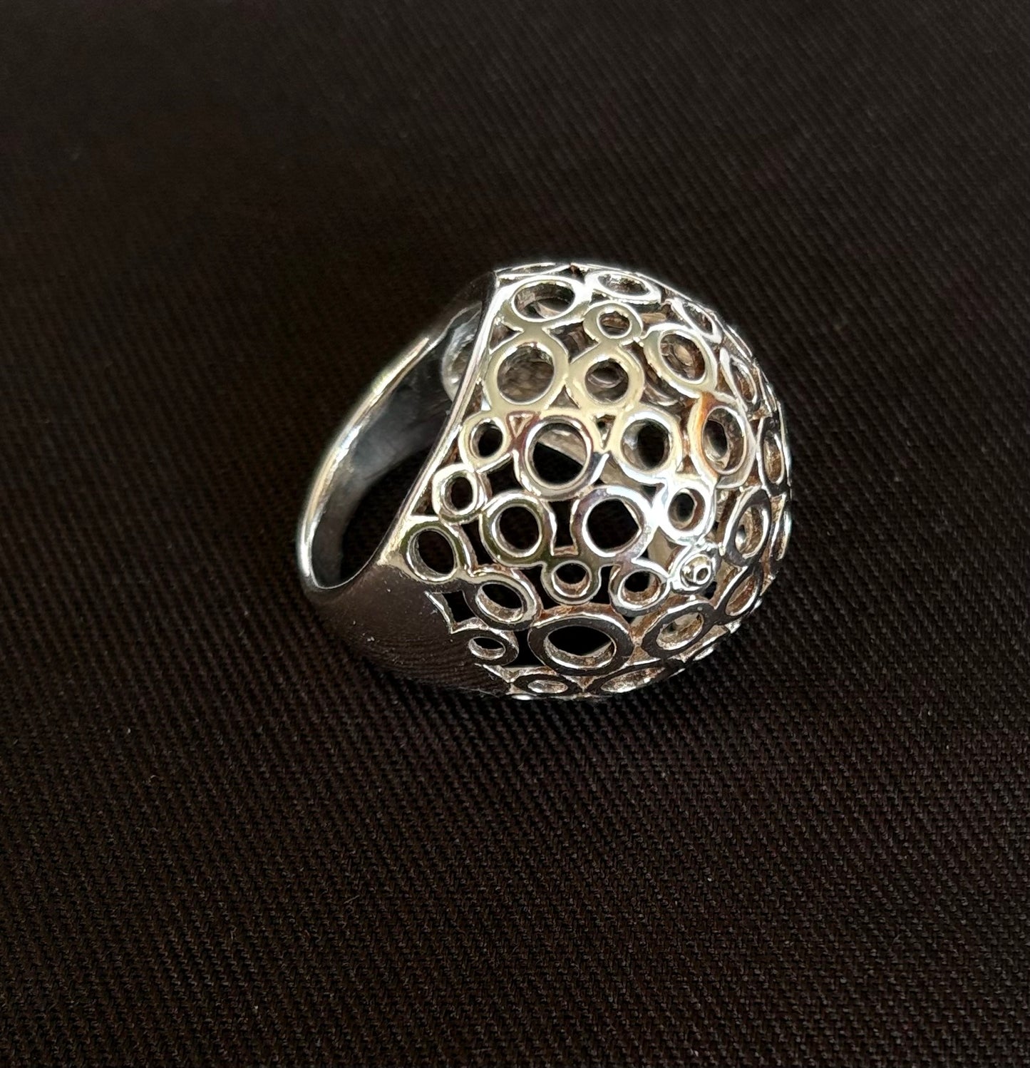 Silver ring with intricate design on a black background