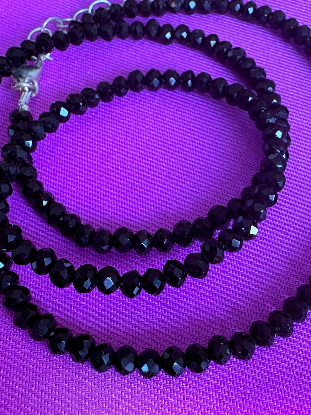 Black spinel beaded necklace on a purple background