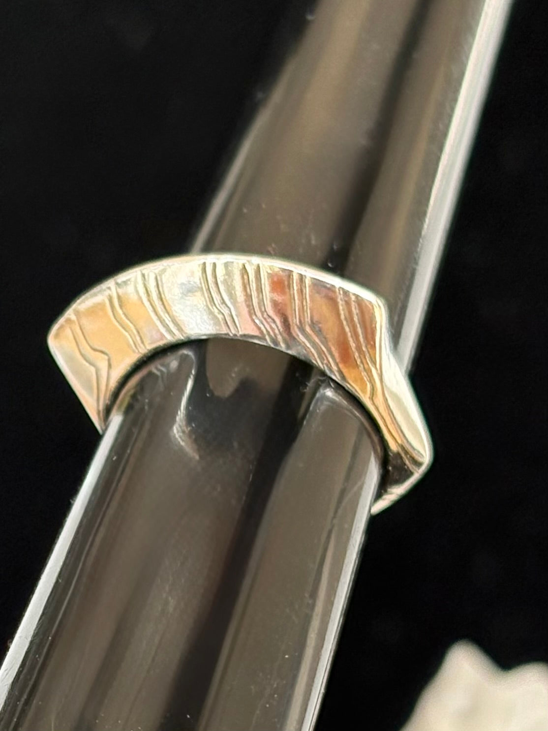 Close-up of a curved sterling silver ring on a black background