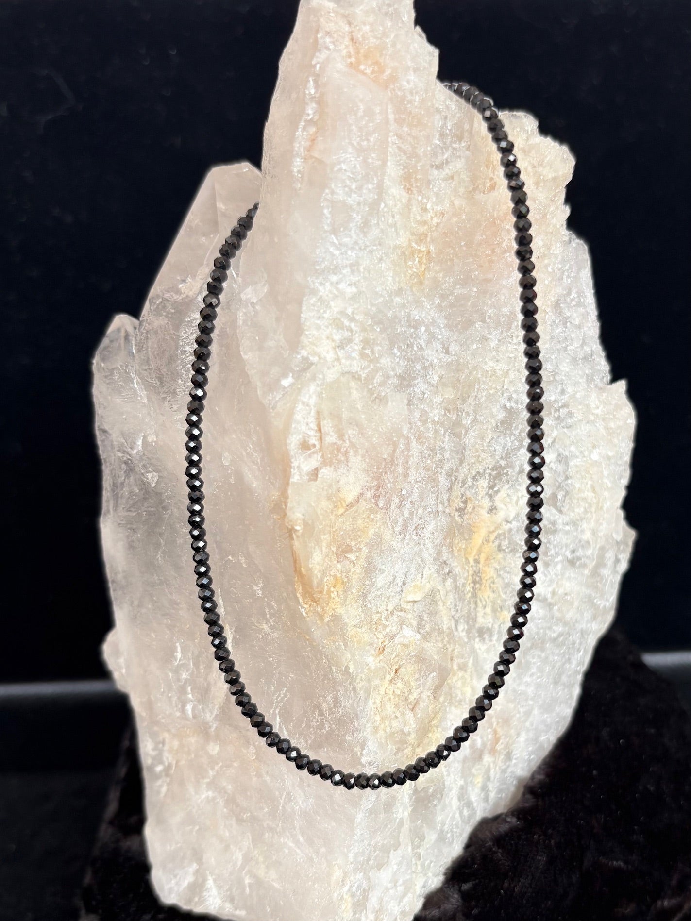 Jolie Esprit black spinel beaded necklace on a white crystal with a dark background