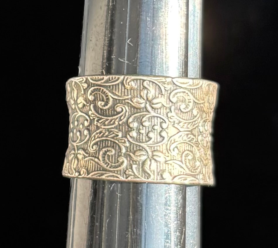 Embossed sterling silver band ring on a dark background