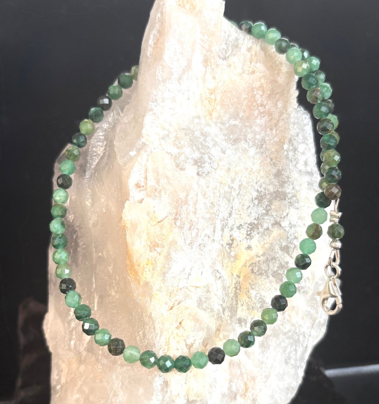 Emerald necklace on a crystal with a dark background