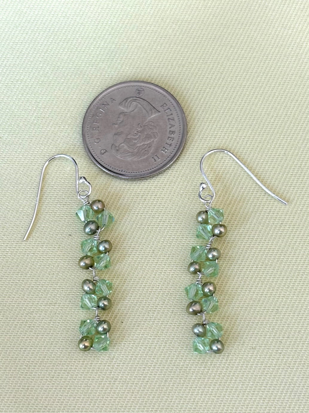 Beaded earrings with green and pearl beads on a light background