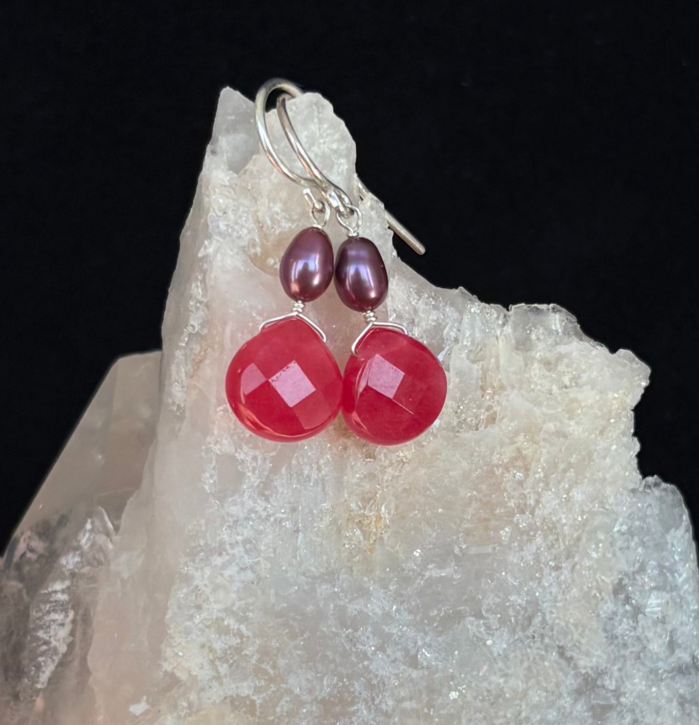 Pink and purple earrings on a crystal rock with a black background
