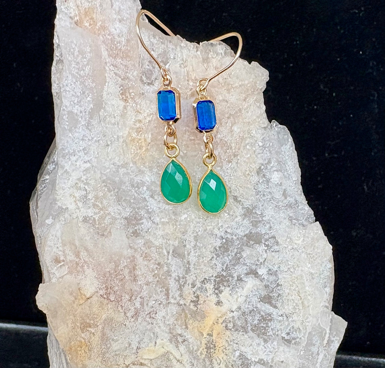 Gold fill earrings with blue and green gemstones on a crystal background