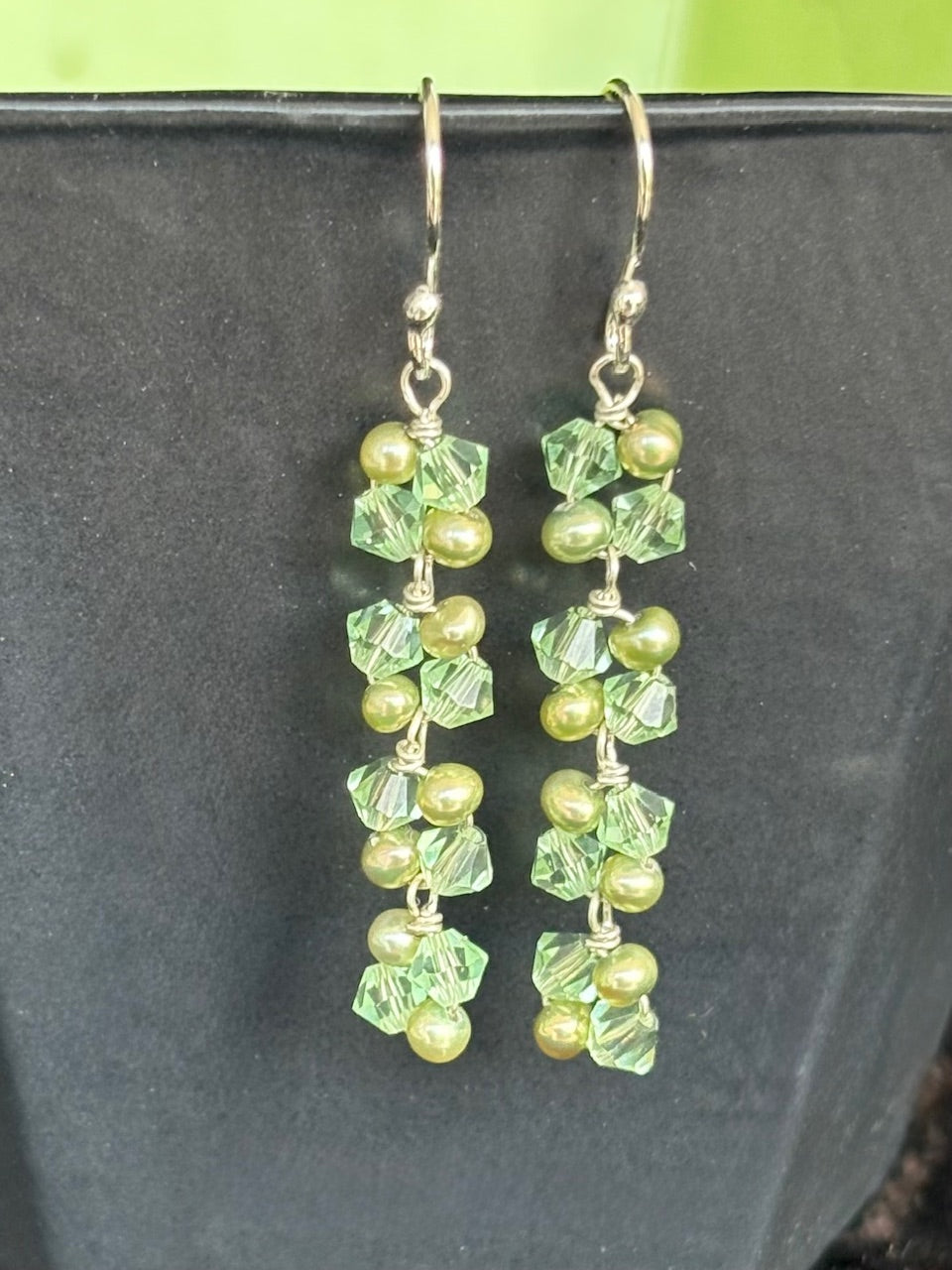 Green pearl and swarovski earrings on a black background