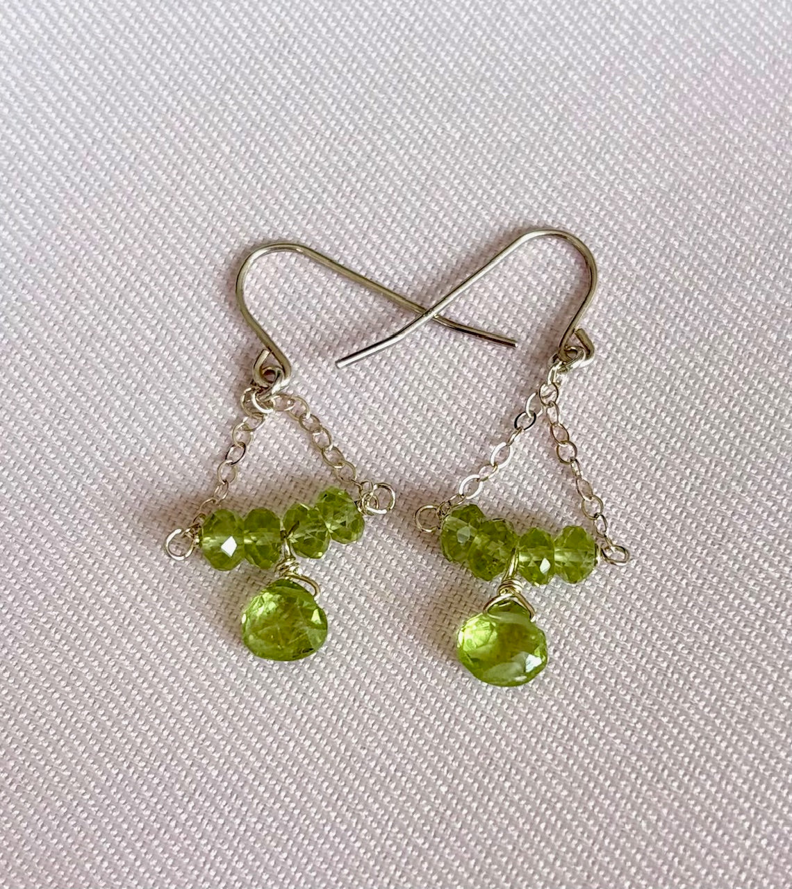 Green gemstone beaded earrings on a white fabric background