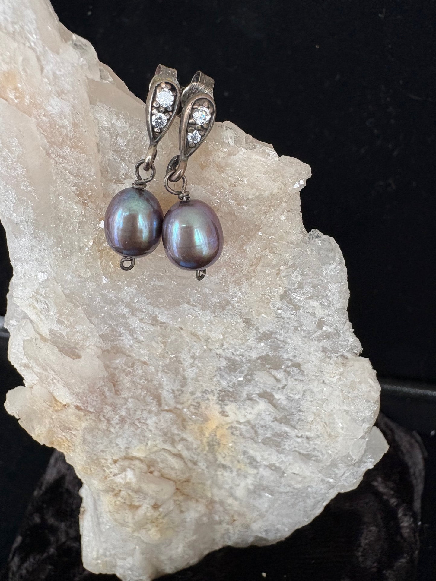 Pearl earrings on a rock with a dark background