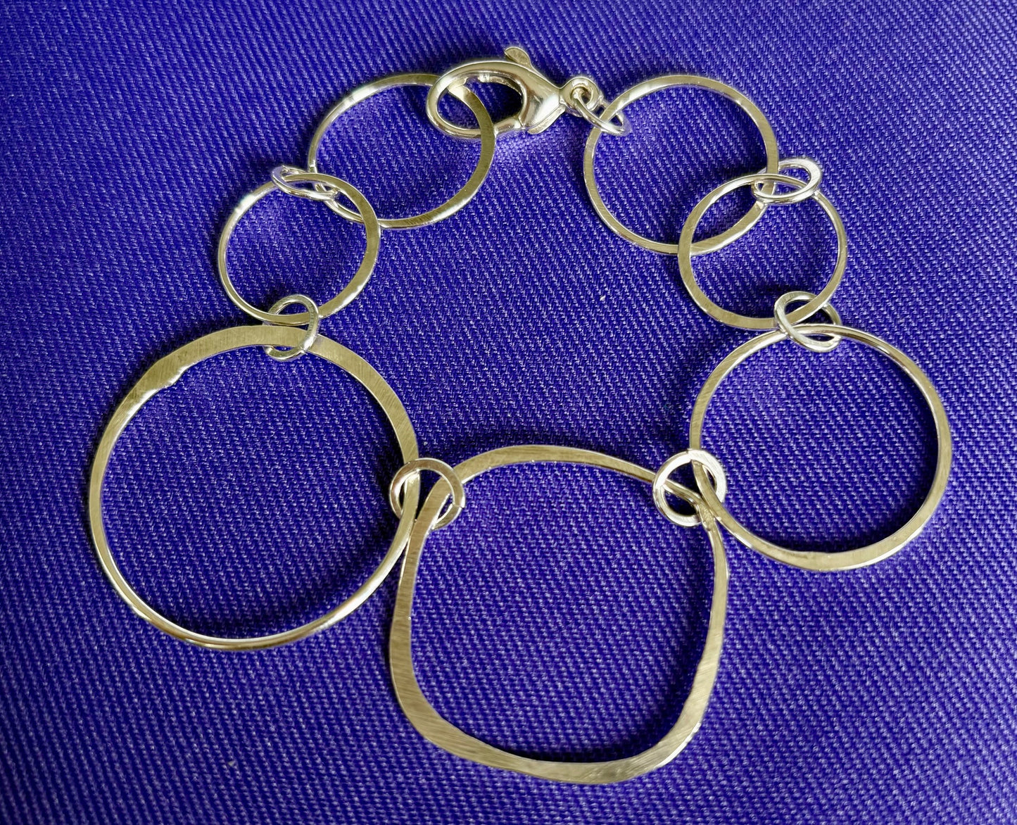 Silver bracelet with interlocking rings on a blue background by Jolie Esprit