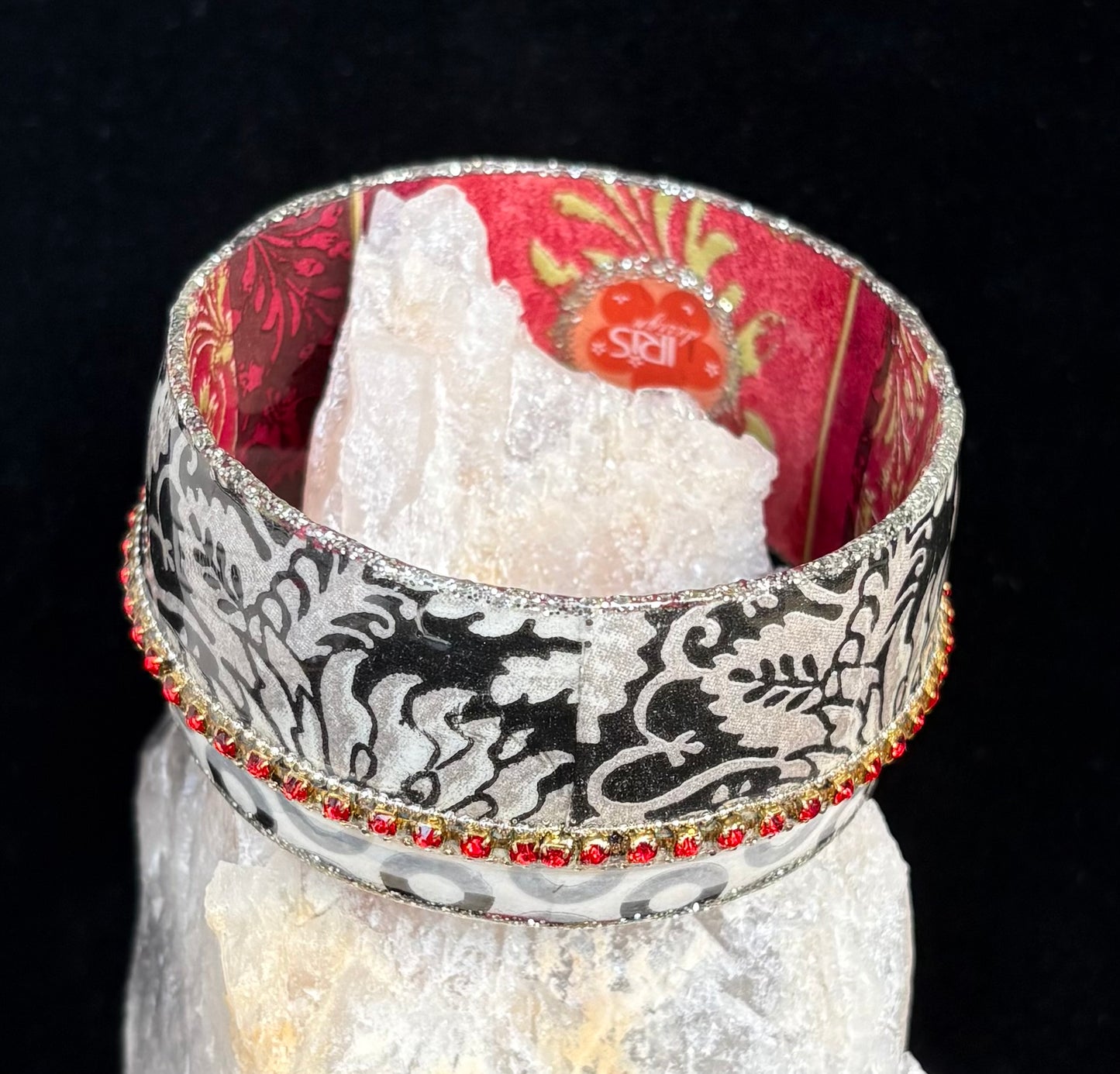 Decorative bracelet with black and white pattern and red accents on a white stone background