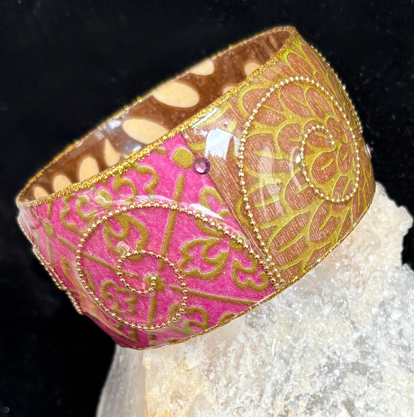 Decorative pink and gold bangle on a black background
