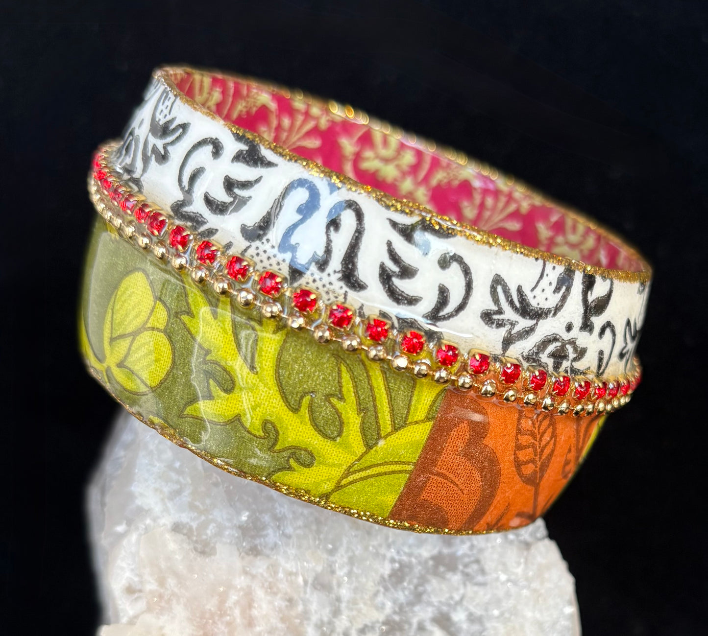 Colorful bangle with intricate designs on a black background by Iris Design