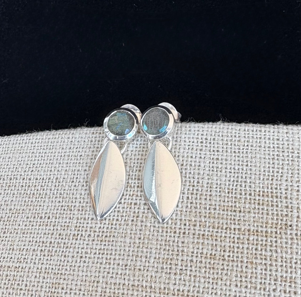 Silver earrings with labradorite gemstones on a textured fabric surface