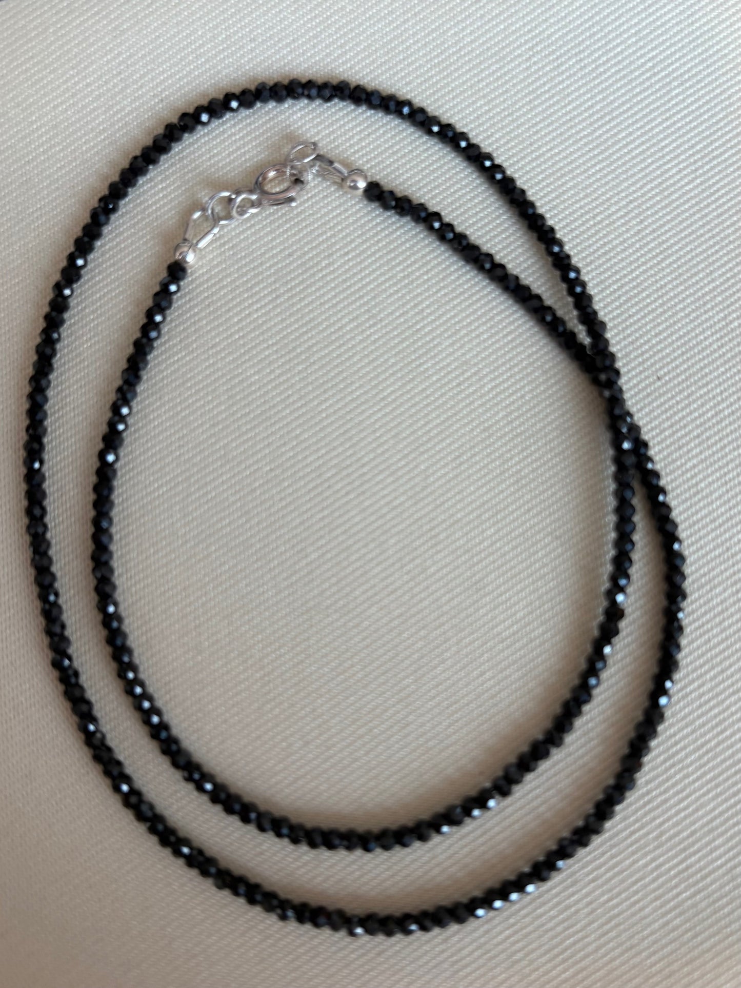 Micro Faceleted Black Spinel beaded necklace on a light beige background