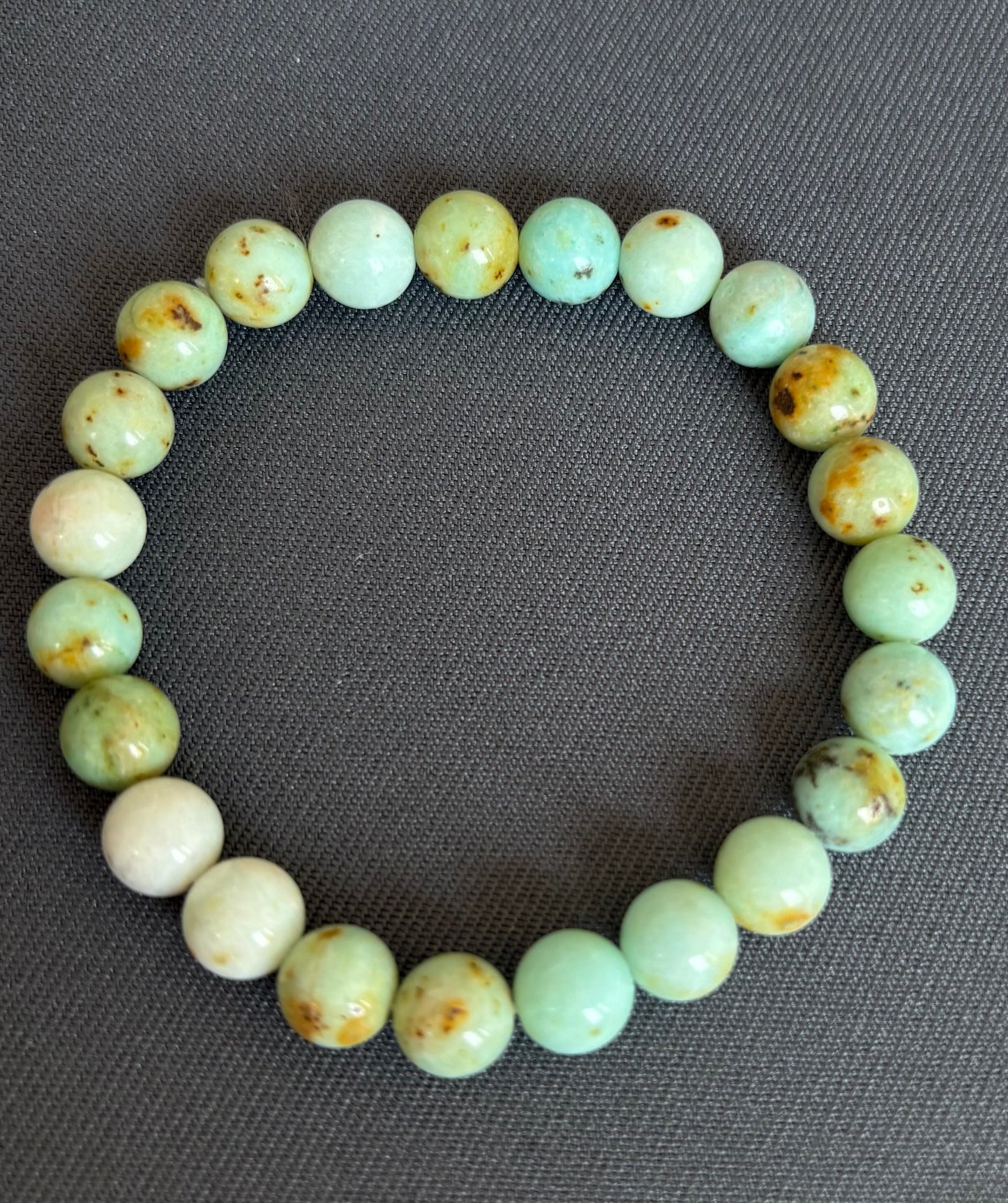 Green beaded bracelet on a gray fabric background