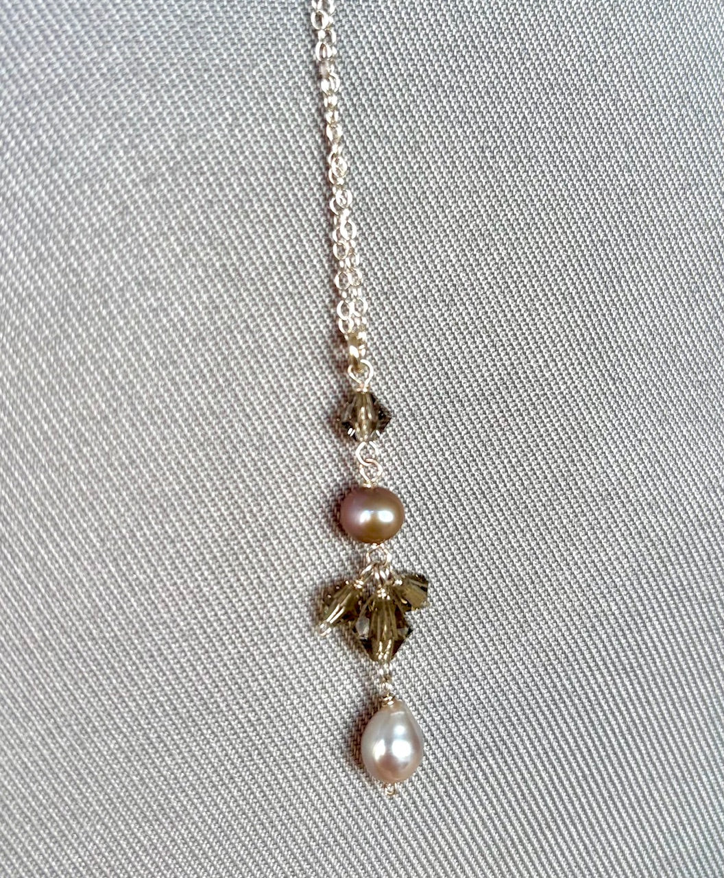 Necklace with pearls and crystals on a gray fabric background