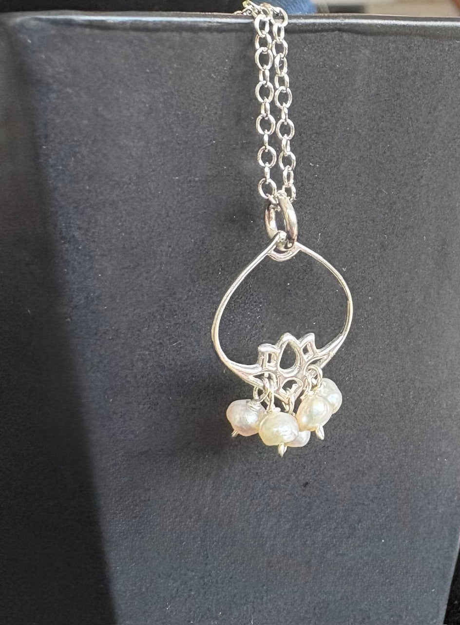 Silver necklace with a pearl pendant on a dark background