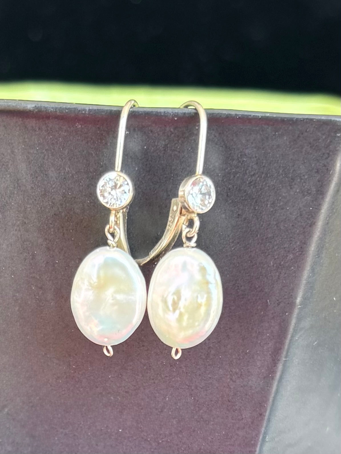 Pearl earrings with pearls and clear gemstones on a dark background