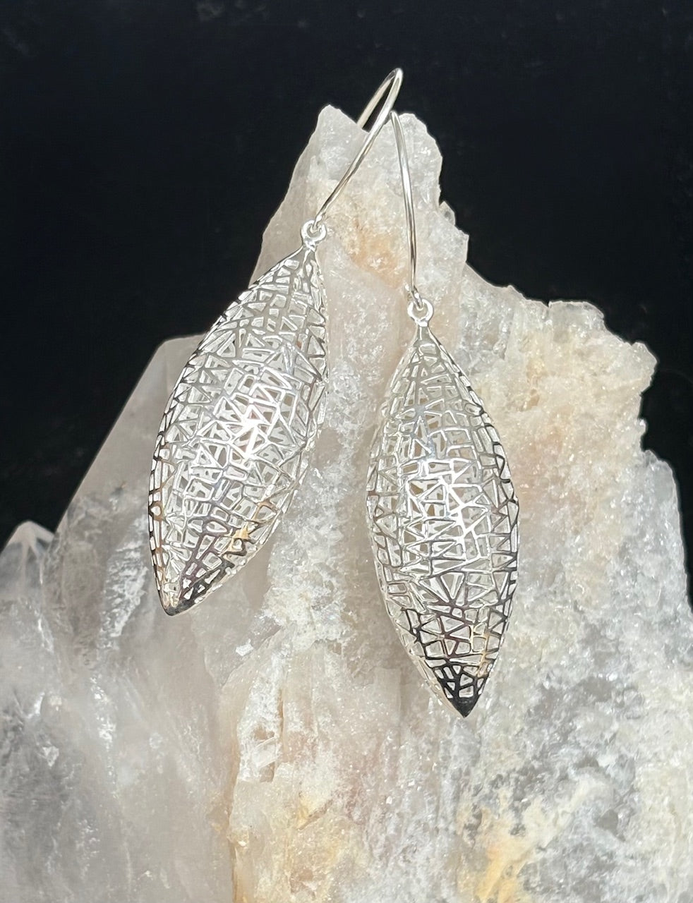 Moroccan inspired sterling silver earrings on a rock with a dark background
