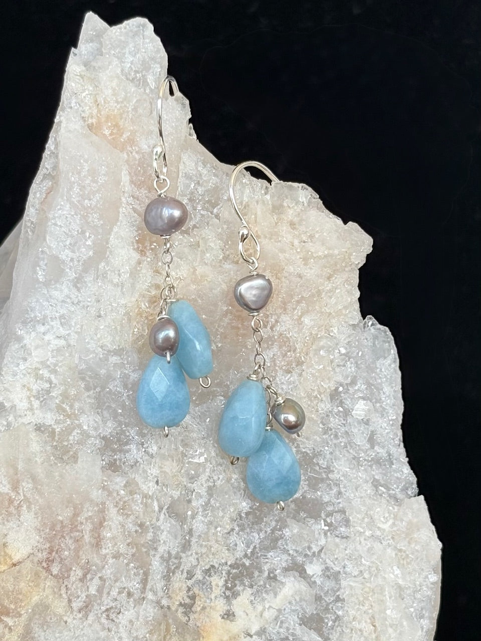 Earrings with amazonite and pearl on a rock background