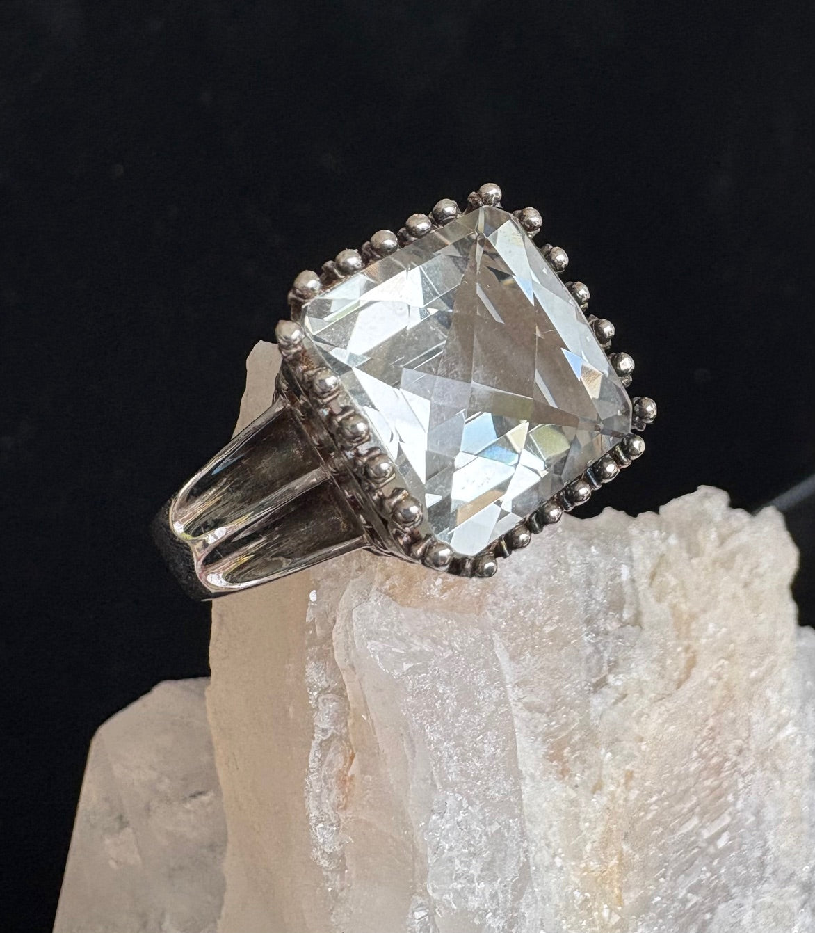 Silver ring with a large green amethyst gemstone on a black background