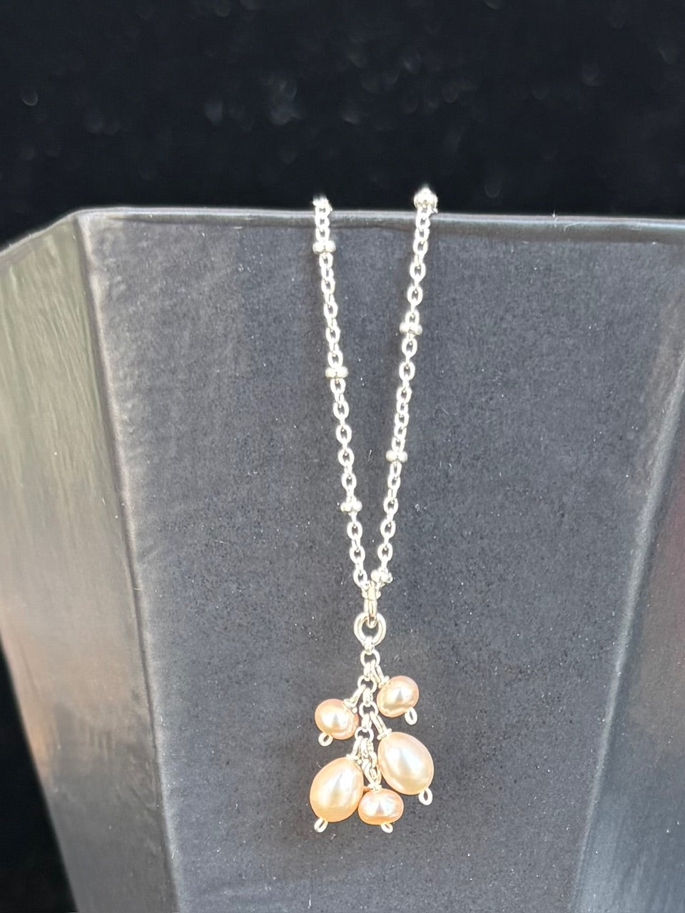 Silver necklace with pearl dangles on a dark background
