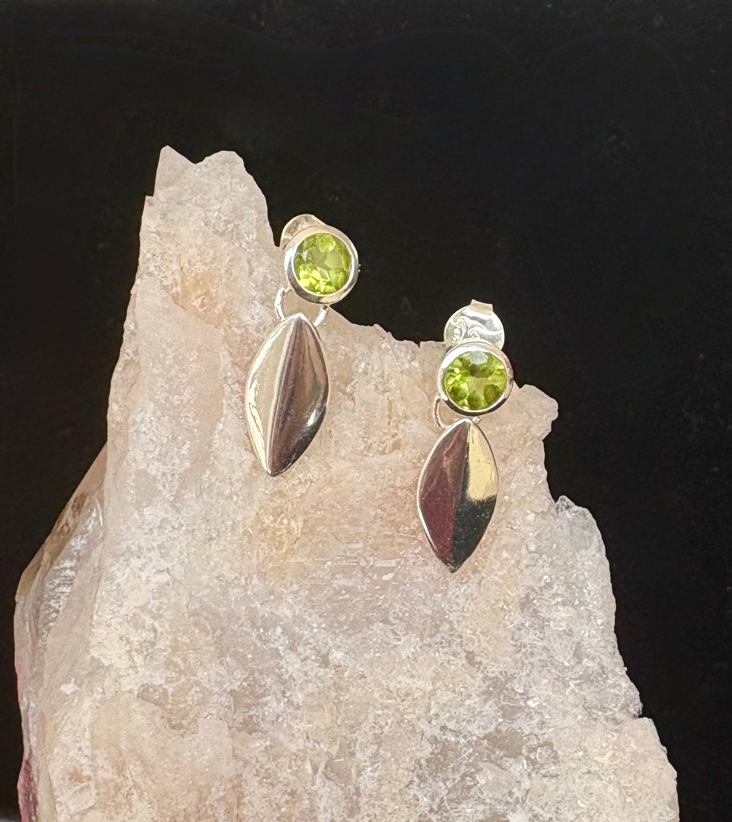 Silver earrings with green gemstones on a crystal background