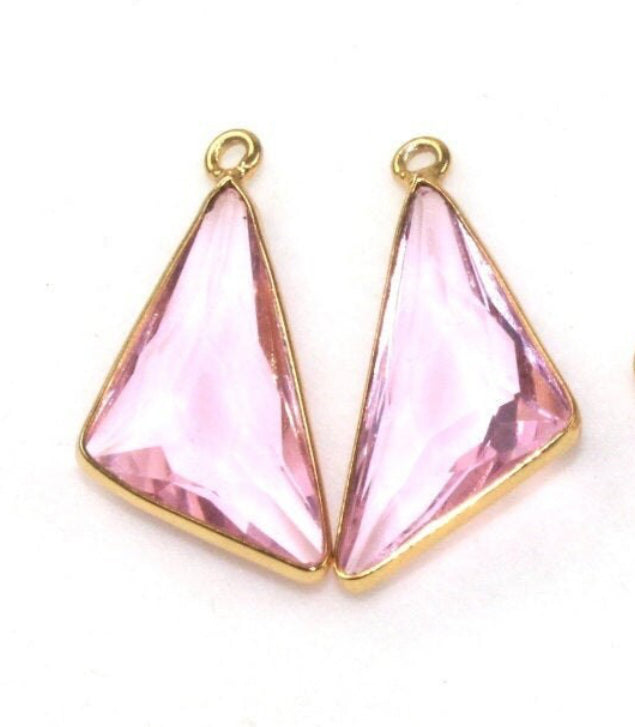 Pink triangular earrings with gold frames on a white background