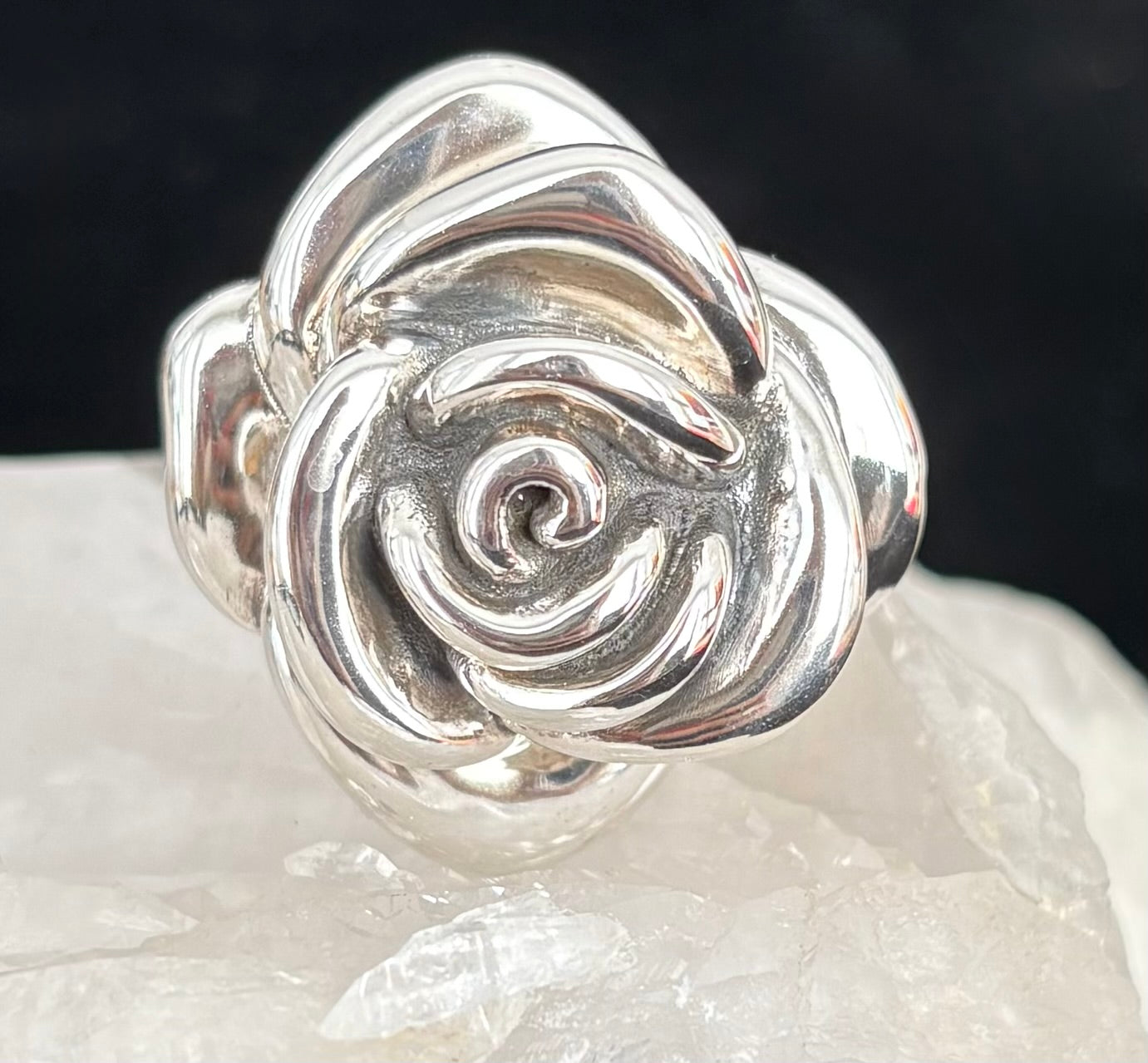 Silver rose-shaped ring on a dark background
