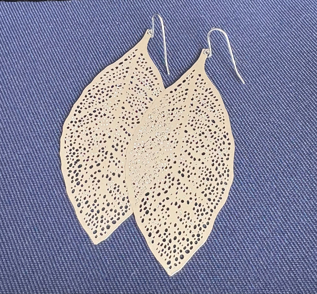 Jolie Esprit leaf-shaped earrings on a blue textured background