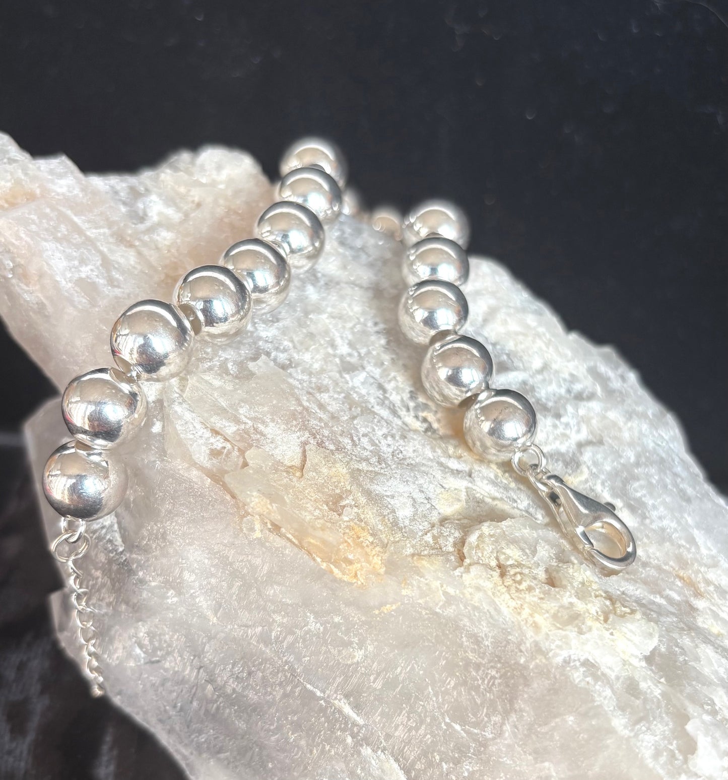 Silver ball bracelet on a textured stone surface