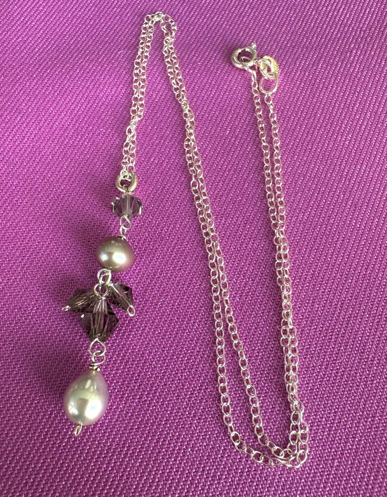 Necklace with pearls and crystal pendant on a purple background