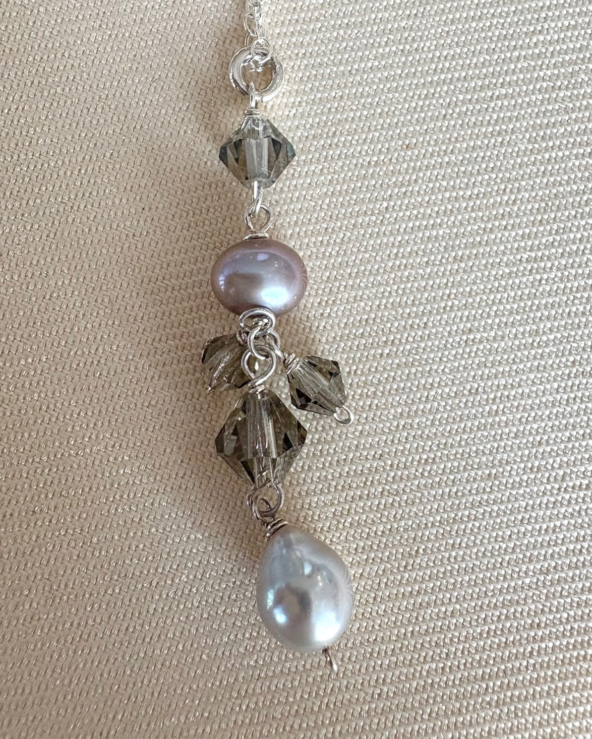 Necklace with pearls and crystals on a beige fabric background
