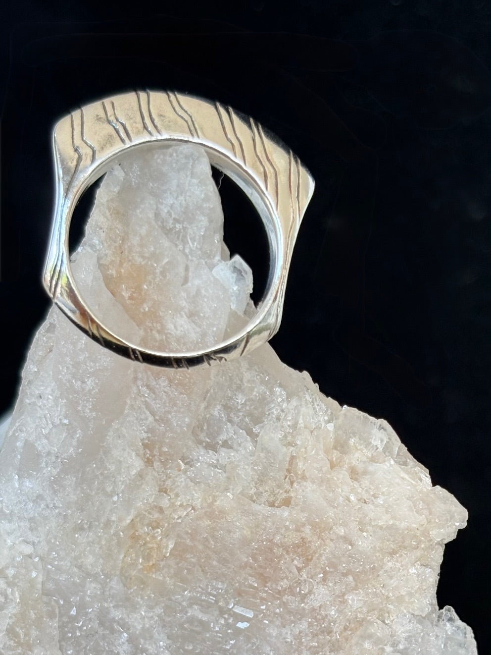 Jolie sterling silver ring with carved design on a crystal rock against a black background