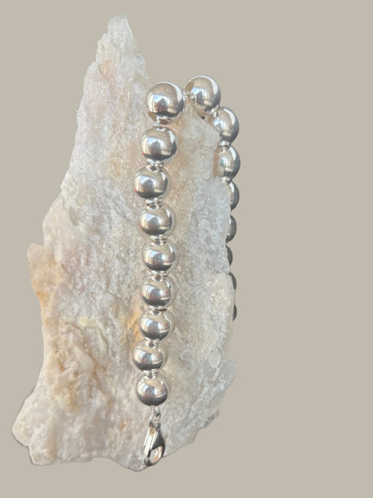 Jolie Esprit Sterling Silver ball bracelet on a rock with a dark background