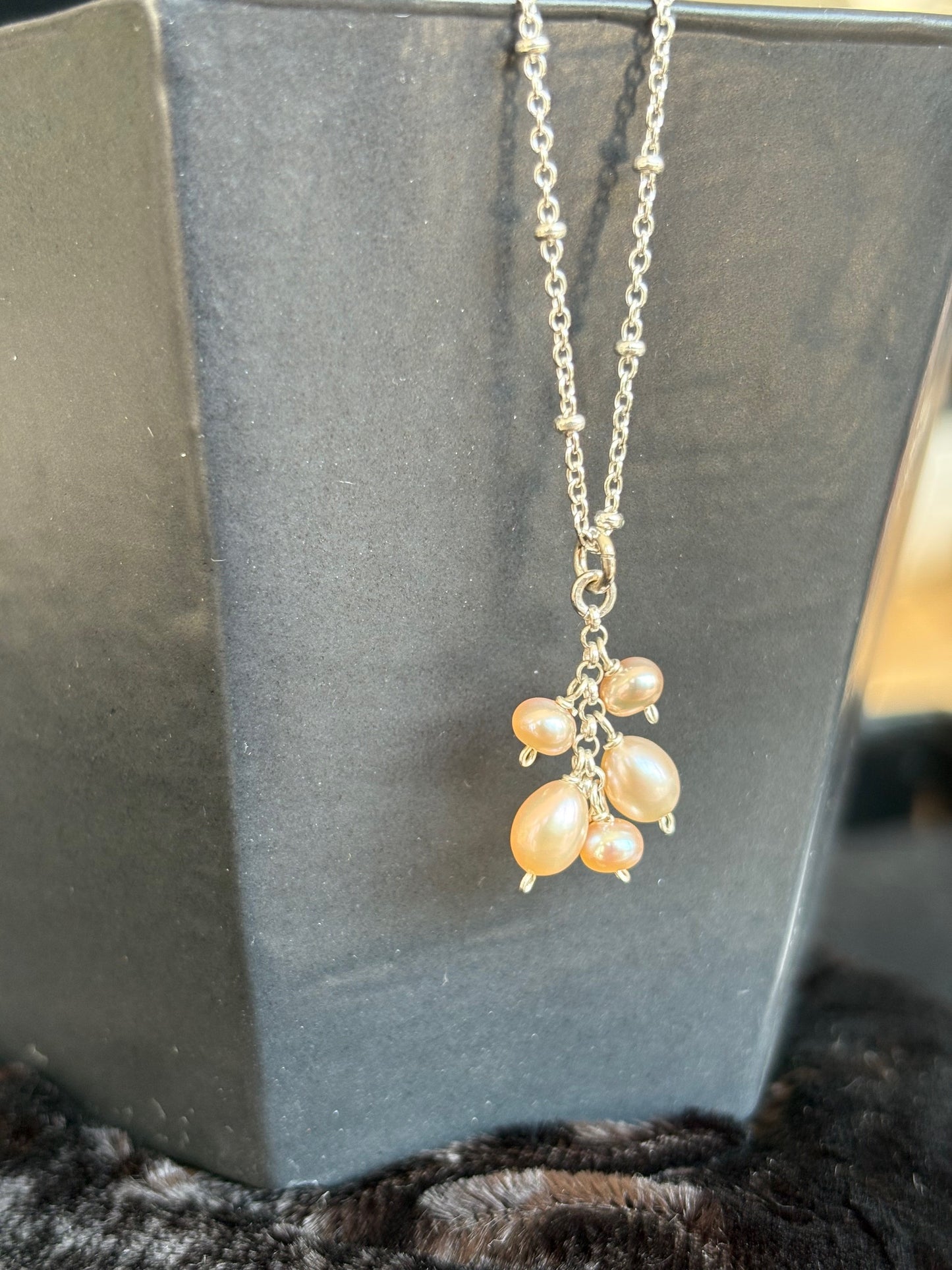 Sterling silver necklace with pears on a dark surface