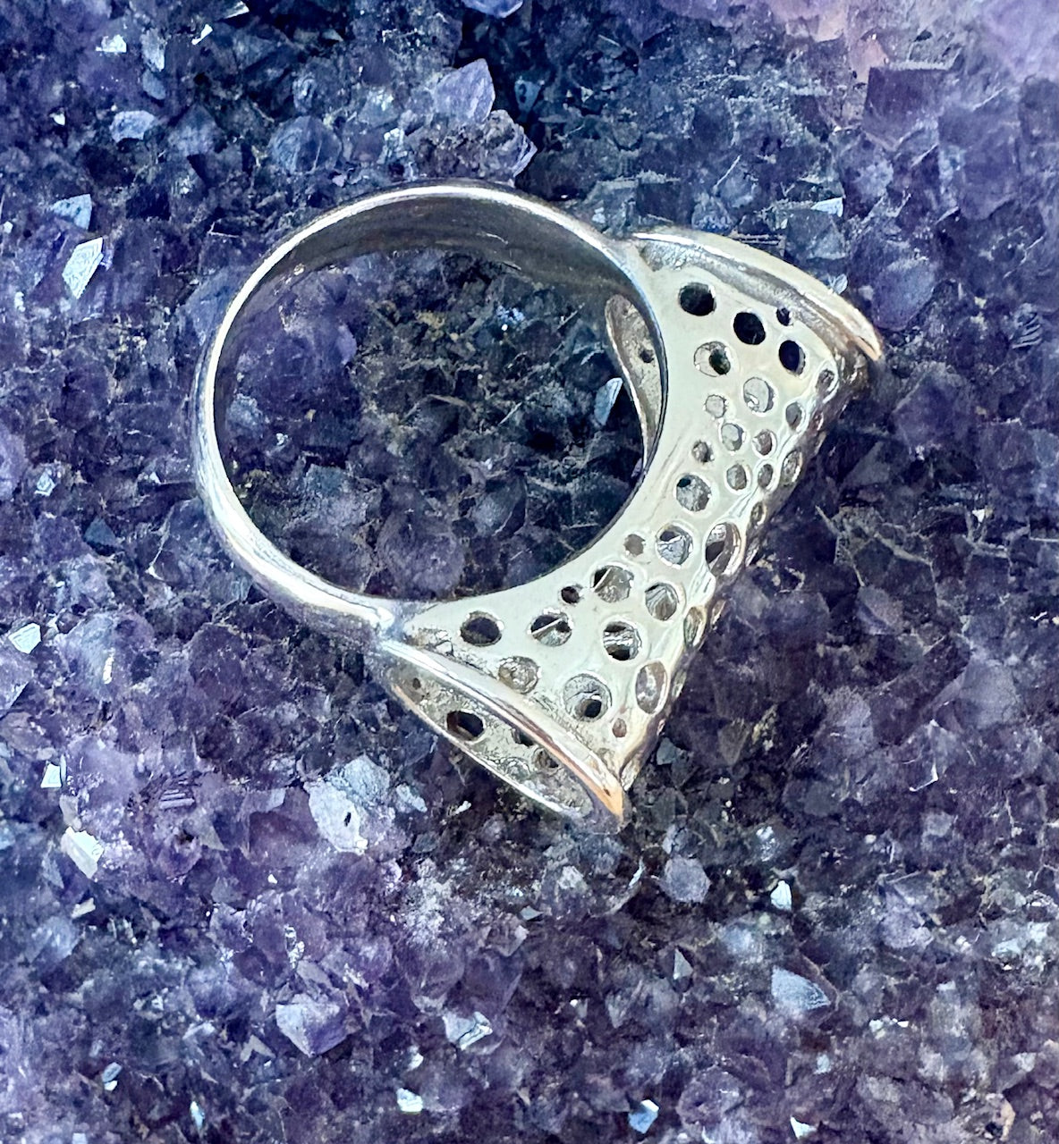Silver ring with geometric design on a purple crystal background